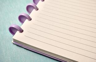 Close up note book with white lined paper page isolated on horizontal copy spaced light blue background. photo