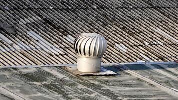 Round metal turbine ventilator system building exterior object isolated on horizontal asbestos roof background. photo