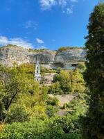 A beautiful church is situated on the top of a scenic hill, which is entirely surrounded by lush trees, creating a serene and tranquil environment that invites reflection and peace photo