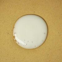 Acne cream gel drop texture isolated on square brown paper background. photo