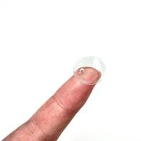 One clear soft contact lens object on finger tip isolated on square white background. photo