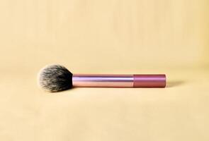 Blush make up brush with pink handle isolated on horizontal brown cream colored background. photo