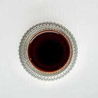 Brown soy sauce condiment and seasoning for sushi in small glass bowl from top angle view isolated on square white background. photo