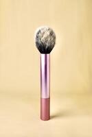 Blush make up brush with pink handle isolated on vertical brown cream colored background. photo