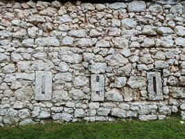 A sturdy stone wall that features a few noticeable holes within its structure, offering a glimpse into the materials used and the passage of time on this building barrier photo