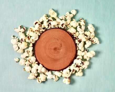 Crunchy salted pop corn snack with round wooden coaster platform object copy space isolated on horizontal background from top angle view. photo