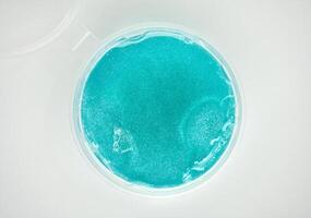 Blue stretchy slime toy object in plastic bowl isolated on horizontal white background from top angle view. photo