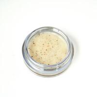 Opened lip scrub in small glass container isolated on square white background. photo