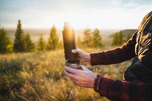 Experience the tranquil beauty of sunrise while enjoying a warm beverage, whether its coffee or tea, from your trusty thermos in nature photo