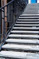 A set of stairs that leads upwards to a particular building, which is equipped with a sturdy metal railing for safety and support while ascending or descending the steps photo