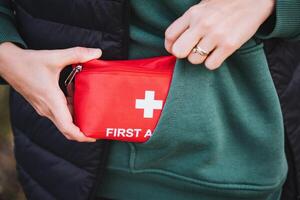 An individual is confidently holding a wellstocked first aid kit, which is conveniently tucked into their side pocket, while wearing comfortable and casual sportswear for their activities photo