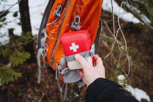 A first aid kit is secured with a strap on the side of the backpack, a small travel first aid kit, equipment for hiking in the forest. photo