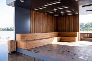 In the corner of a room, there is a beautifully crafted wooden bench sitting gracefully next to a tranquil body of water, creating a serene atmosphere for relaxation and contemplation photo