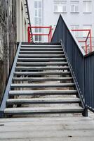 As you approach the building, youll see prominent stairs leading to the entrance, accented by a vibrant red railing that enhances the overall aesthetic of the structure photo