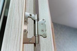 This image shows a closeup of a wellattached door hinge on a beautifully crafted wooden door, highlighting the exceptional craftsmanship and quality materials in its design photo