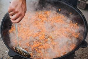 A person is carefully stirring a pot of delicious food using a ladle in their kitchen, ensuring that the ingredients blend together perfectly for an amazing meal to be enjoyed later photo