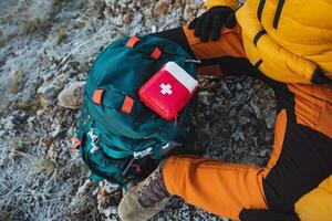 Top view of a red first aid kit, which is lying on a backpack, a tourist in the mountains uses a first aid kit. photo