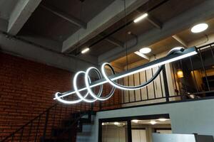 Featuring a modern industrial office with a unique spiral LED light fixture suspended above the staircase. Ideal workspace blending minimalist and modern design elements photo