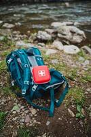 A motor vehicle is parked on electric blue grassland with a backpack and first aid kit on top. The landscape is filled with plant and soil, perfect for recreation and travel photo