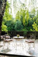 The patio is furnished with a table and chairs, nestled among trees, providing a serene space for outdoor activities and socializing, perfect for gatherings and leisurely pursuits photo