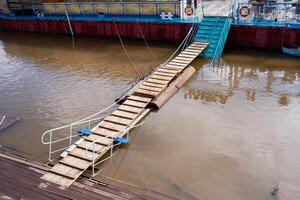 A sturdy wooden bridge constructed over a flooded river, designed to allow safe passage and connections despite the flowing water, showcasing impressive engineering and material use photo
