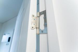 This image features a detailed closeup of a door hinge attached to a pristine, white door, showcasing the intricate mechanics and design that helps it function efficiently photo