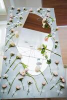 A table with a rectangular mirror surrounded by flowers and twigs photo