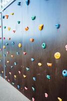 A vibrant climbing wall adorned with an array of colorful rocks of various shapes and sizes, inviting climbers to challenge themselves while enjoying the spectacular scenery photo