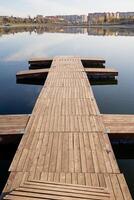 A picturesque wooden dock extends gracefully into a serene lake, while a vibrant city skyline stands majestically in the background, creating a beautiful contrast of nature and urban life photo