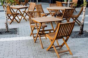 Outdoor furniture set with wooden folding tables and chairs on a brick sidewalk photo