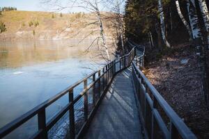Metal bridge with railing in the national park, walking path along the pond, autumn in the mountains, iron bridge, place for outdoor recreation. photo