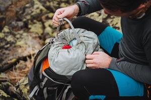 Man on rock packing backpack with soil and grass background photo