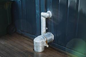 A metal pipe is resting on a wooden floor adjacent to a door, creating a noticeable presence in the rooms design and construction. It implies a possible plumbing function or feature photo