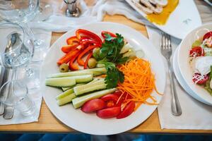 A plate of vegetables on a table with a fork and spoon photo