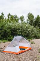 In the forest, a tent is set up, harmonizing with the trees, grass, and the clear sky. This natural environment provides a serene backdrop for camping and immersing in nature photo