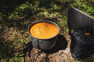 Set a pot of tasty soup on the grass near a chair to make a serene and welcoming setting that complements the natural beauty around. Enjoy a delightful meal amidst natures splendor photo