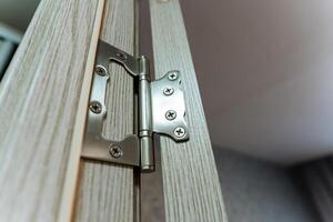 This image features a closeup view of a door hinge that is attached to a beautifully crafted wooden door, showcasing the intricate details and materials used in its construction photo