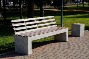In a serene park setting, there exists a sturdy concrete bench that features a beautifully crafted wooden seat, inviting visitors to sit and enjoy the tranquil natural surroundings photo