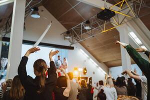 A crowd in the room with their arms in the air enjoying the entertainment event photo