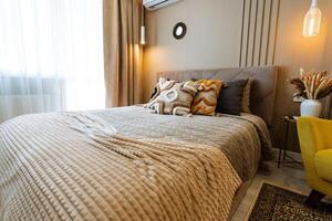 This cozy bedroom includes a comfy bed for restful sleep, a chic reading chair for relaxation, a practical work table for productivity, and a bright window for delightful natural light photo