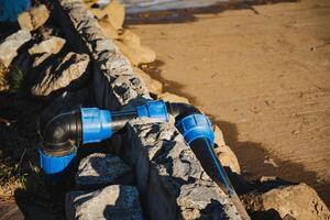 A blue pipe is securely attached to a solid stone wall, providing an interesting visual contrast between the vibrant color of the pipe and the earthy texture of the wall photo
