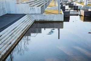 In a flooded area, a dock reflects beautifully upon the surface of the water, mirroring a nearby building and creating a striking urban landscape that truly captivates the observers eye photo