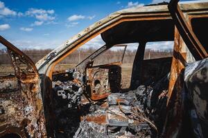 burnt fat of a car abandoned on the side of the road in a field, a burnt car, a car crime, destruction of property. photo