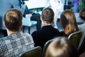Crowd sitting in chairs sharing fun conversation at an event photo
