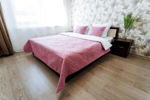a bed with a pink comforter and pillows in a bedroom photo