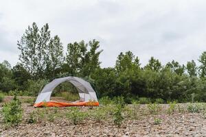 Immerse yourself in a camping adventure by setting up a tent in peaceful natural surroundings, away from the city. Explore nature and find serenity in the wilderness photo