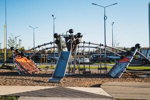 In a parking lot, there is a vibrant playground that features a tall slide alongside a challenging climbing wall, providing fun and recreational opportunities for children and families photo