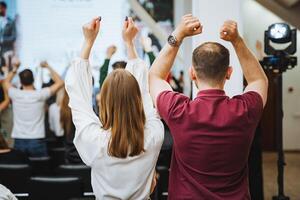 A group of people are joyfully gesturing with raised hands at a leisure event photo