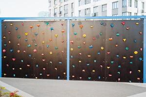 There is a climbing wall featuring an extensive array of climbing holds affixed to its surface, creating an exciting and engaging environment for climbers to practice their skills photo