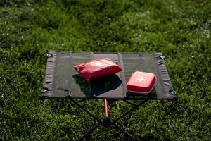 A wellorganized first aid kit is placed on a sturdy folding table that is set up on the grass, ensuring easy access for any emergencies that may arise during outdoor activities and events photo